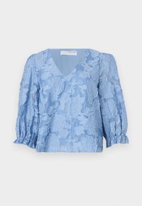 Lys blå bluse med blomstrede blonder, V-hals og puffede trekvartlange ærmer. Blød, gennemsigtig stof med rynkede manchetter.