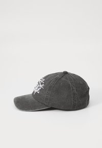 Grå baseballcaps med buet skjerm, seks-panel design og hvit brodert geometrisk mønster på fronten. Justerbar stropp bak.