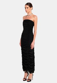 Zwarte strapless maxi-jurk met geplooide details, een aansluitende pasvorm en een gladde textuur. Draag met zwarte hoge hakken sandalen.