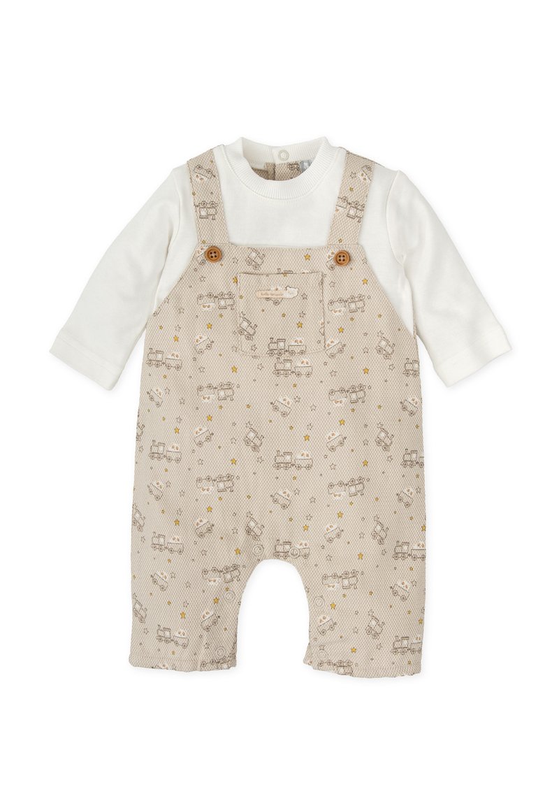 Peto beige con vehículos y estrellas impresos, con botones de madera, y una camiseta de manga larga blanca debajo. Material de algodón suave.