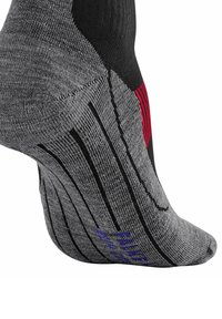 Calcetín atlético gris con acentos en negro y rojo, que presenta talón y punta reforzados, tela texturizada y rayas para agarre y soporte.