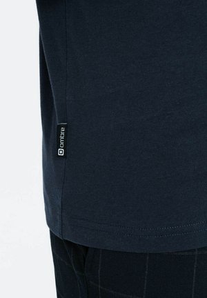 T-shirt en coton bleu marine à coupe droite, avec une petite étiquette noire "ombre" à l'ourlet et une texture lisse.