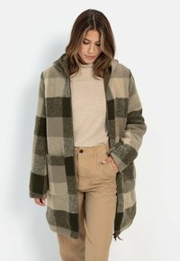 Karo-Wollmantel in Beige- und Oliventönen, mit Reißverschluss, zwei Fronttaschen und Kapuze. Strukturiertes Gewebe mit Karomuster.