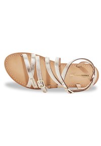 Sandalias de cuero en plata metálica con múltiples correas estrechas sobre una plantilla beige, con un pequeño detalle de hebilla dorada.