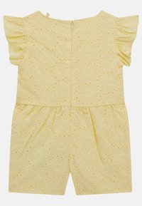 Žlutý květinový overal s krátkými volánovými rukávy, peplum pasem, dekoračním otvorovým vzorem a zapínáním na zip na zádech.