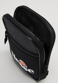 Czarna materiałowa saszetka na zamek, z szarą przednią częścią i białym logo. Wnętrze wyłożone czarnym materiałem. Kompaktowy design.