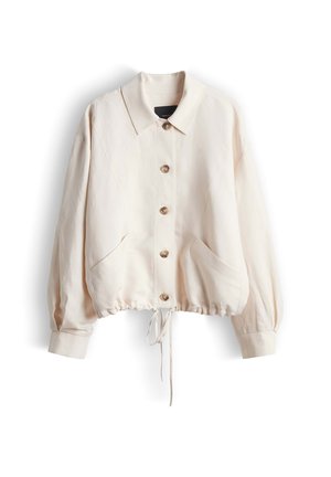 Veste beige clair à manches longues boutonnée, avec col, deux poches avant et ourlet à cordon ajustable.