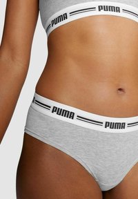 Graue Baumwoll-Sportunterwäsche mit einem weißen Bund, der ein schwarzes "PUMA"-Logo und Streifen aufweist. Glatte Textur, niedrige Passform.