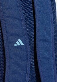 Spallacci del verde imbottito con schienale in rete e un logo Adidas bianco sul lato sinistro dello spallaccio.
