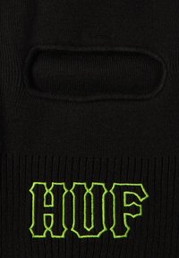 Balaclava neagră tricotată, cu o deschidere orizontală pentru ochi și „HUF” brodat în verde neon sub deschidere.