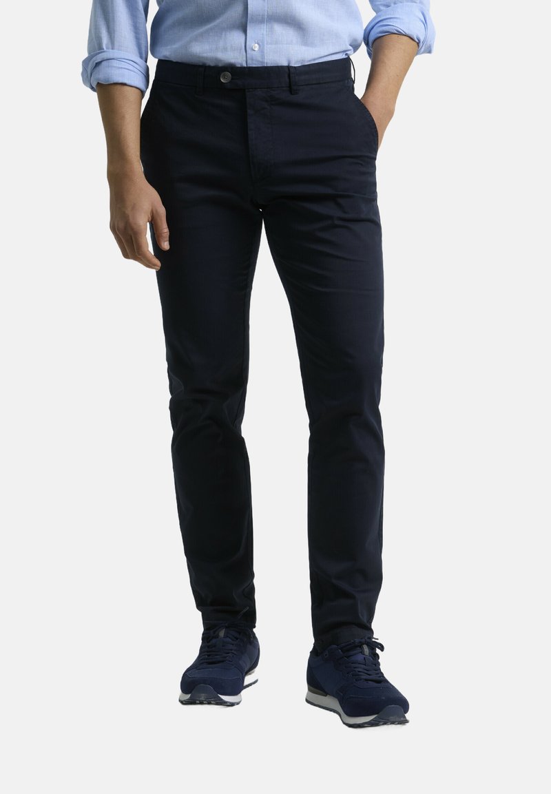 Chinos azul marino fabricados en algodón suave. Cuentan con corte recto, bolsillos laterales y cierre de botón. Combinados con zapatos deportivos oscuros.