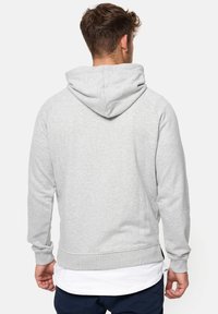 Sudadera gris con bolsillo canguro, puños y dobladillo acanalados, capucha con cordones y tejido suave y texturizado. Detalle de costura visible en las costuras.