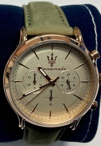 Chronograph-Uhr mit Gehäuse aus Roségold, grünem Lederarmband und cremefarbenem Zifferblatt, das drei Hilfszifferblätter und ein Emblem aufweist.