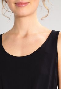 Schwarzes ärmelloses Tunika mit einem Rundhalsausschnitt. Glattes, leichtes Material mit einem minimalistischen Design, das eine schlichte, elegante Silhouette präsentiert.