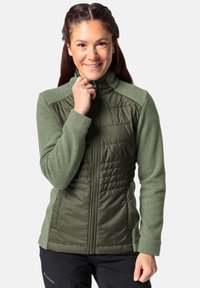 Olijfgroene jas met een gewatteerde voorkant, fleece mouwen en een hoge kraag. Ritsluiting met logo-accent op de borst.