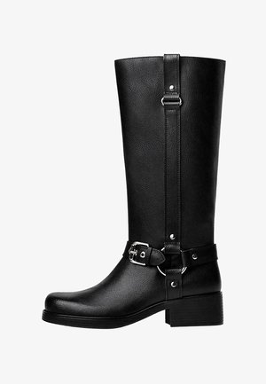 Höga svarta låtsasläderstövlar med rund tå, accentdetalj i form av spänne och en kraftig klack. Slät textur och vertikal söm på skaftet.