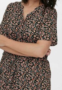 Black floral dress with short sleeves, featuring pink and blue flowers. Gathered neckline and an adjustable drawstring waist. Lightweight fabric.