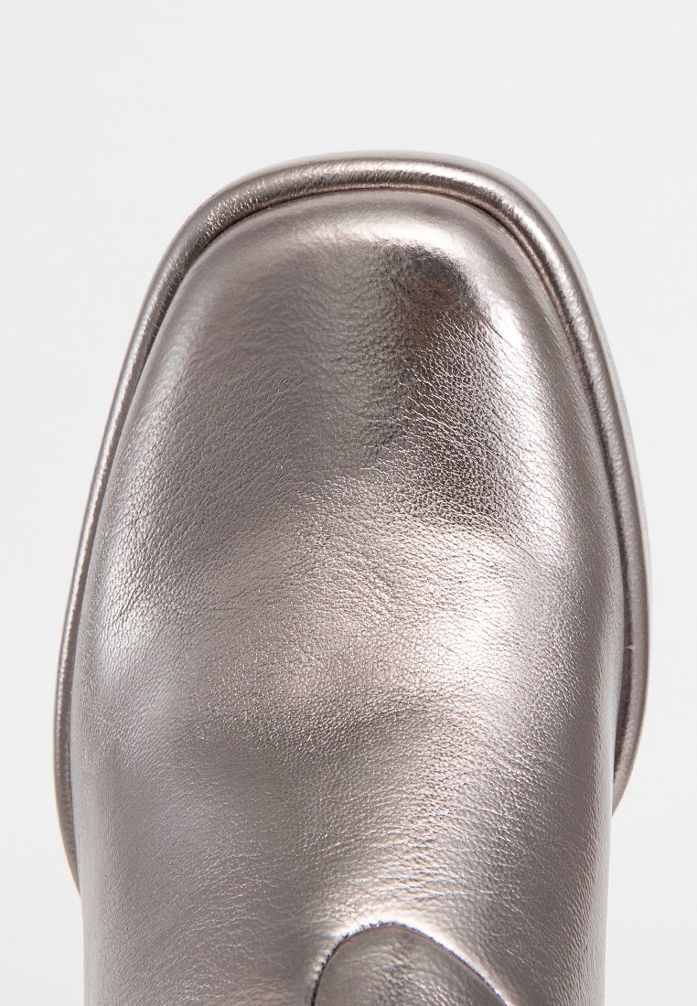 Chaussure en cuir gris métallique avec un bout arrondi, texture lisse et éclat subtil. Présente une couture surélevée le long du bord pour le détail.