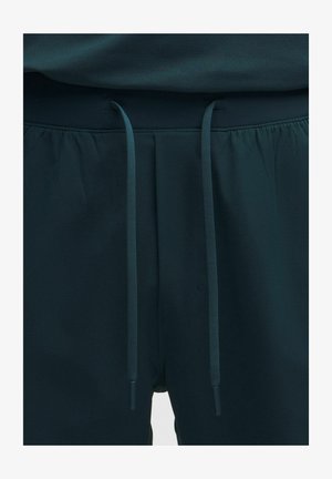 Temno zelene kratke hlače z elastičnim pasom in nastavljivimi vrvicami, izdelane iz lahkega blaga, s tekočo teksturo in minimalnimi detajli.