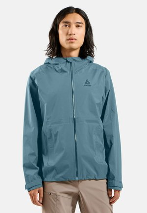 Veste légère et imperméable de couleur bleu discret, dotée d'une fermeture éclair à l'avant, d'une capuche réglable et d'une broderie de logo sur la poitrine. Texture lisse.