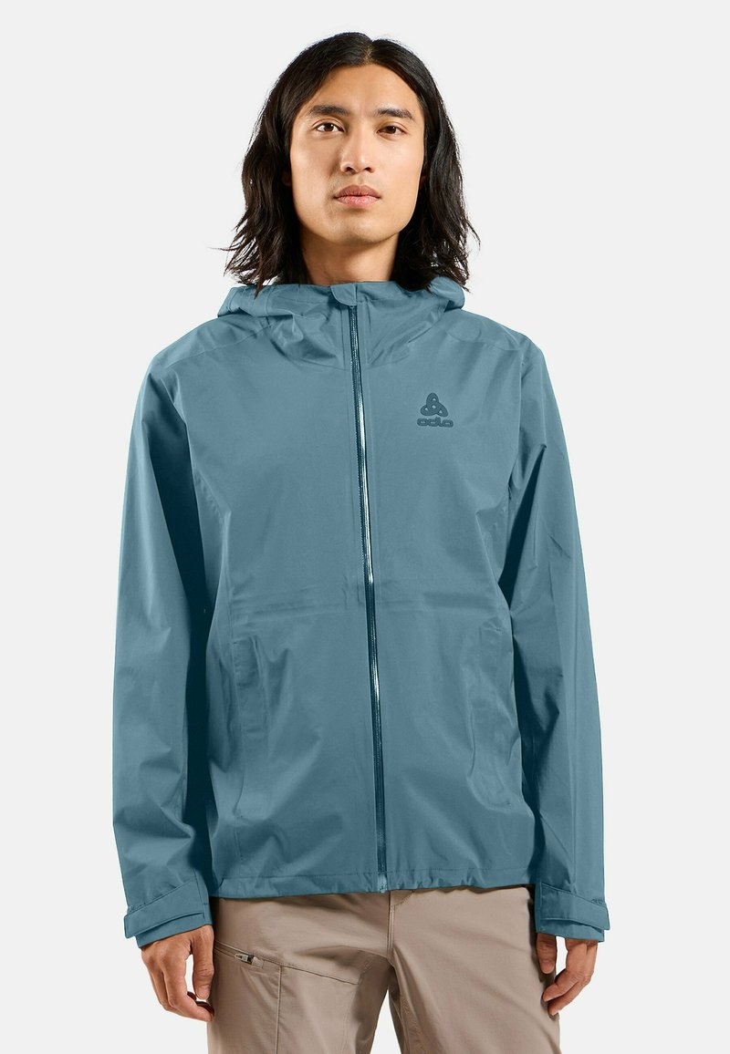 Veste légère et imperméable de couleur bleu discret, dotée d'une fermeture éclair à l'avant, d'une capuche réglable et d'une broderie de logo sur la poitrine. Texture lisse.