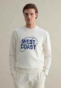 Felpa bianca con grafica "WEST COAST" in blu navy. Presenta un colletto rotondo, maniche lunghe e una finitura morbida e testurizzata.