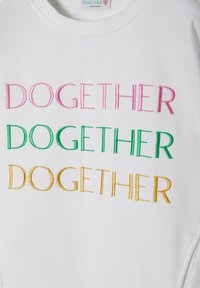 Sweatshirt bianco con la scritta "DOGETHER" ricamata in rosa, verde e oro. Design a girocollo con tessuto morbido e testurizzato.