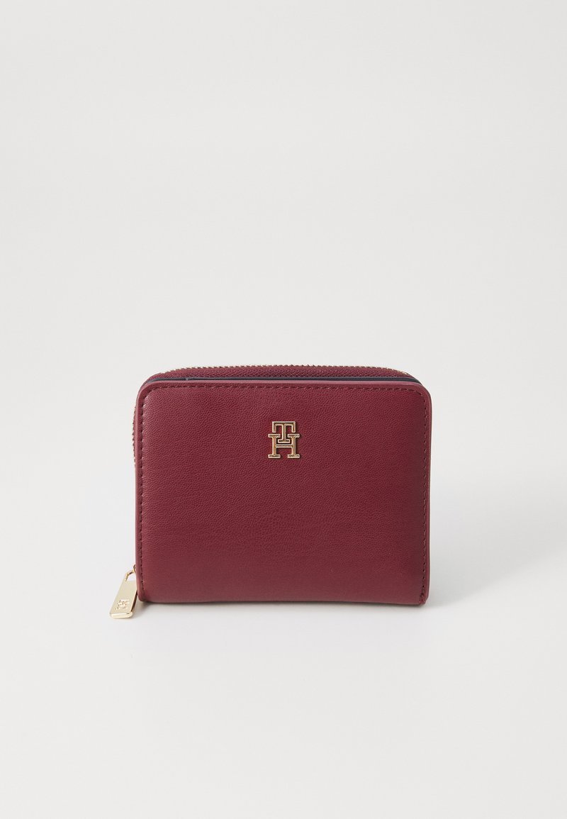 Burgundy leather wallet with gold hardware and logo. Rectangular shape with zipper closure and textured surface for added grip.