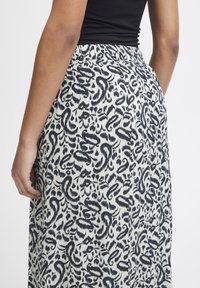 Maxikjol med blommönster i svart och kräm, med en hopdragen elastisk midja och lätt tygtextur.