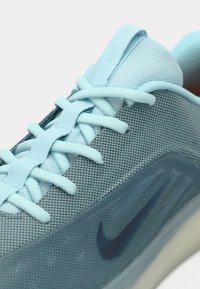 Svetlomodrá športová obuv s hornou časťou z oka, textúrovanou medzipodrážkou a tmavomodrým logom Nike Swoosh na boku. Šnúrky ladia s farbou vrchnej časti.