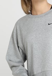 Grauer Sweatshirt mit Raglanärmeln, aus weichem Stoff gefertigt. Verfügt über ein schwarzes Nike-Logo auf der Brust. Einfaches, lässiges Design.
