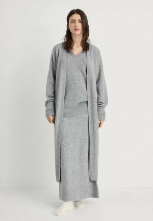 Completo da loungewear grigio a maglia composto da un cardigan lungo, un maglione a collo a V e una gonna lunga con polsini e orlo a costine. Tessuto morbido e testurizzato.
