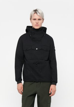 Black pullover jacket in a matte finish, featuring a high collar, two chest pockets with buttoned flaps, and a front drawstring hem.