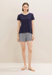 Haut à manches courtes bleu marine avec un col blanc, associé à un short rayé bleu marine et blanc. Tissu léger, coupe décontractée, sans motifs visibles.