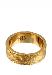Guldring med en strukturerad, matt yta och en polerad insida. Har en subtil logotyp ingraverad inuti ringen.