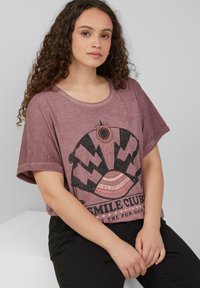 Kurzarm, kastanienrotes T-Shirt mit einem schwarzen Grafikdesign, das eine Sonne und Text zeigt. Weicher, strukturierter Stoff mit lässiger Passform.