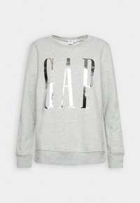 Sweat-shirt gris clair à manches longues avec grand logo métallique argenté « GAP » imprimé sur le devant, col rond et poignets côtelés.