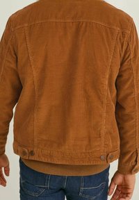 Braune Cordjacke mit gerippter Textur, Knopfakzenten am Saum und klassischem Design. Schlichte Rückansicht mit sichtbaren Nähten.