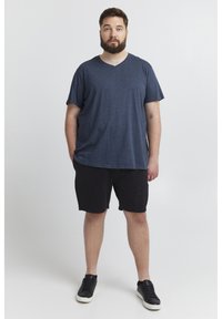 Marineblå v-hals t-skjorte med korte ermer, satt sammen med svarte shorts og svarte joggesko. Uformell, avslappet passform og myk stofftekstur.