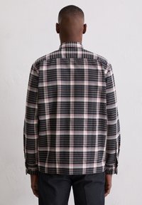 Hemdkleid mit schwarzem, weißem und rosa Karomuster. Lange Ärmel, klassischer Kragen und gerader Saum. Hergestellt aus gewebtem Stoff.