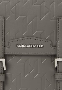 Borsa in pelle grigia con motivo geometrico in rilievo, hardware in argento e una placca con il marchio "KARL LAGERFELD."