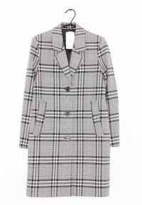 Cappotto a scacchi in bianco e nero con design doppiopetto, ampio colletto, due tasche frontali e chiusura con tre bottoni.