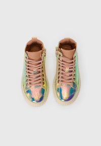 Et par iriserende høyhælte sneakers med beige snøringer og såler, sett ovenfra på en hvit bakgrunn.