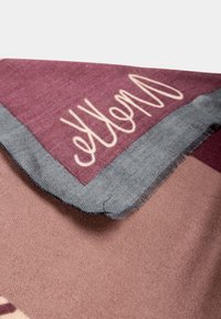 Sciarpa di tessuto morbido con motivo geometrico bordeaux e rosa, bordata da bordi grigi e rifinita con frange.