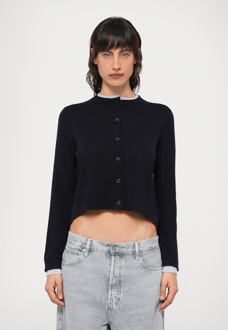 Cardigan scurt negru cu guler rotund, cu guler gri deschis, cu închidere completă cu butoane și mâneci lungi, fabricat dintr-un material tricotat moale.