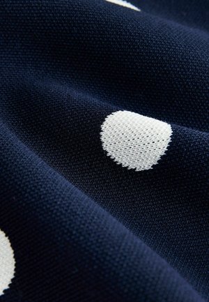 Navy fabric with a knitted texture, featuring large white polka dots. The material appears soft and stretchy, with visible loops in the weave.