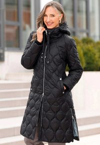 Zwarte gevoerde jas met kap, voorzien van een ritssluiting aan de voorkant, een trekkoord bij de hals en zijzakken. Gladde textuur met een ruitpatroon.