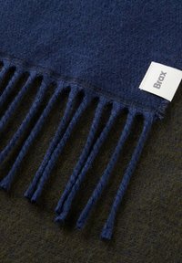 Marineblauwe wollen sjaal met franjes. Beschikt over een wit genaaid label met "Brax." Zachte textuur, compacte weving en geen zichtbare patronen.