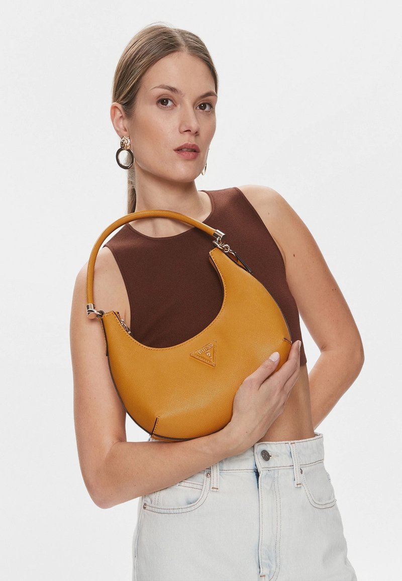 Borsa gialla realizzata in materiale testurizzato; forma curva con un manico corto; presenta un dettaglio del logo vicino alla parte superiore; indossata sottobraccio.