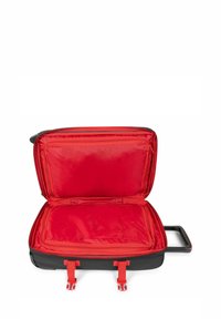 Černý kufr na kolečkách s červeným vnitřkem, se zipovými kapsami a dvěma zajišťovacími popruhy. Obsahuje teleskopickou rukojeť pro snadnou přepravu.